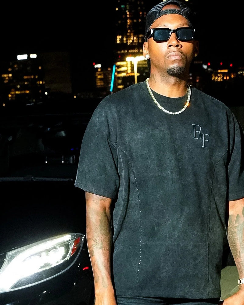Silent Construct Signature Tee — tight model crop: washed-black heavyweight tee with tonal RF chest embroidery, black Mercedes and Atlanta skyline at night. Designed in Atlanta.